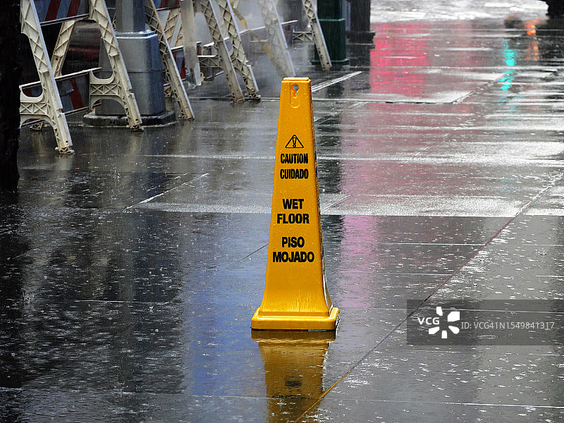 曼哈顿雨天人行道上的黄色塑料“小心地滑”警示牌图片素材