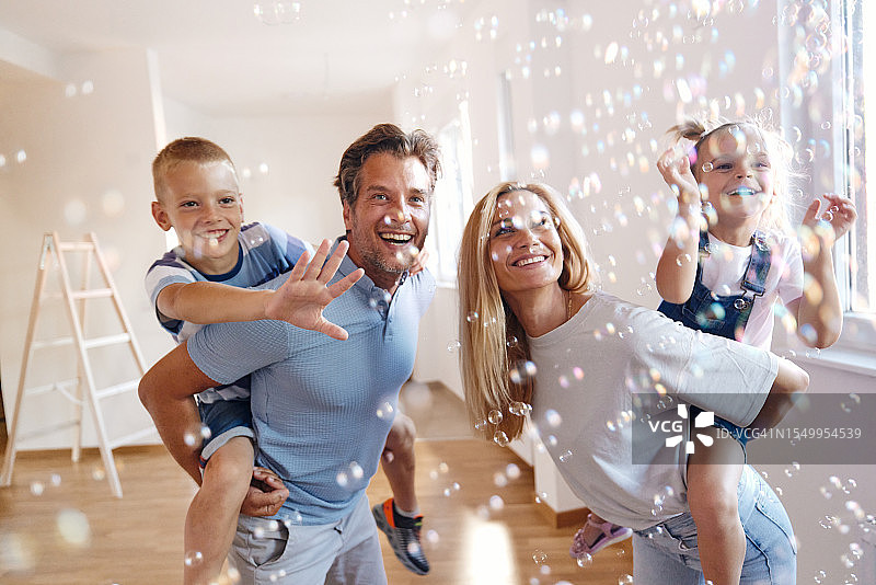 在新公寓里在泡泡中玩耍的快乐家庭图片素材