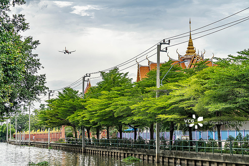 在泰国曼谷寺庙上空飞行的飞机图片素材
