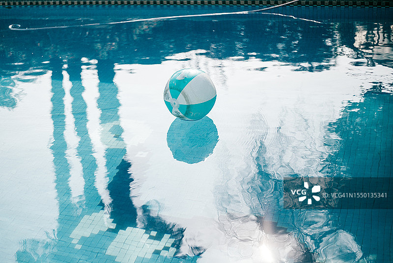 漂浮在泳池中的蓝色沙滩球图片素材