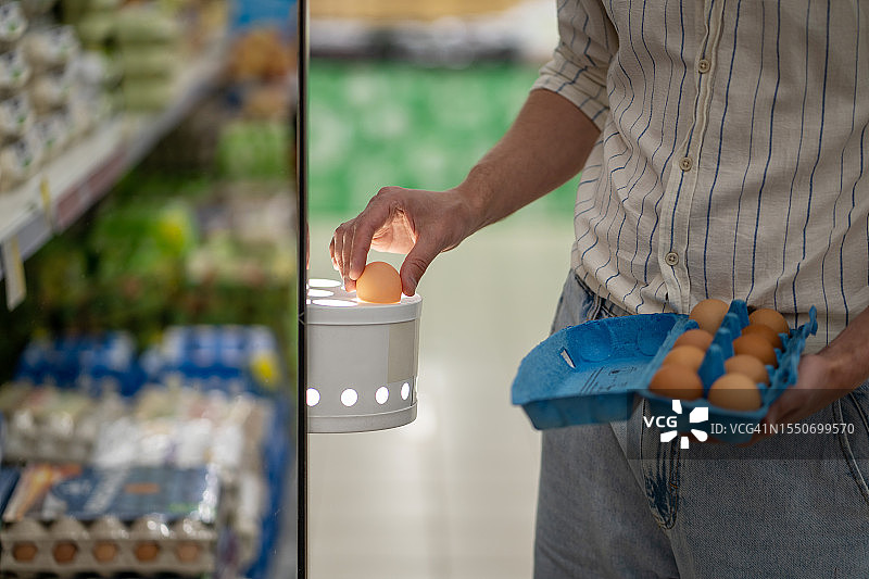 男人在超市用灯检查鸡蛋新鲜度的手图片素材