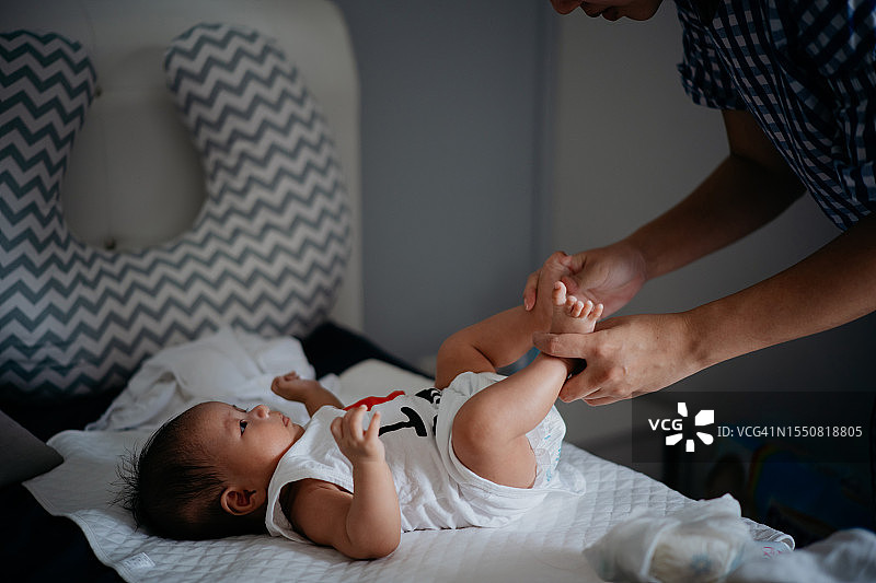母亲在床上为新生婴儿按摩脚部图片素材