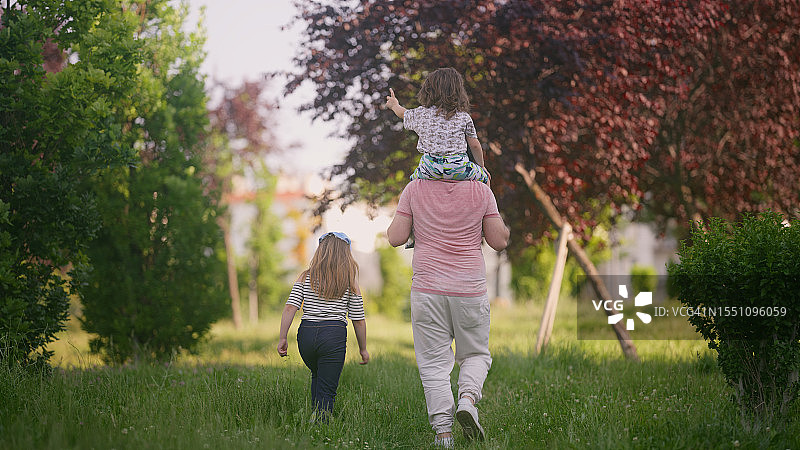 父亲在公园里照顾女儿和儿子，一起散步图片素材