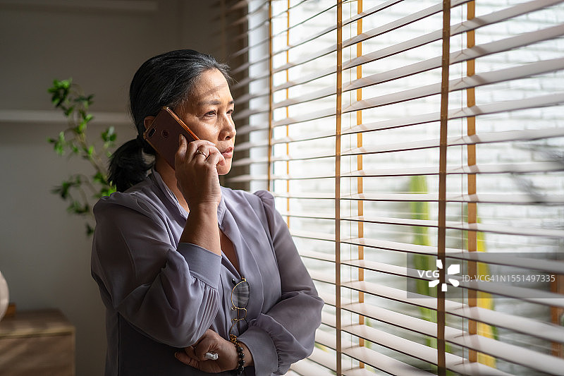 老妇人使用智能手机给孩子和孙子打电话，充满怀旧之情图片素材