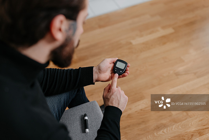 使用可靠血糖监测设备的年轻男人图片素材
