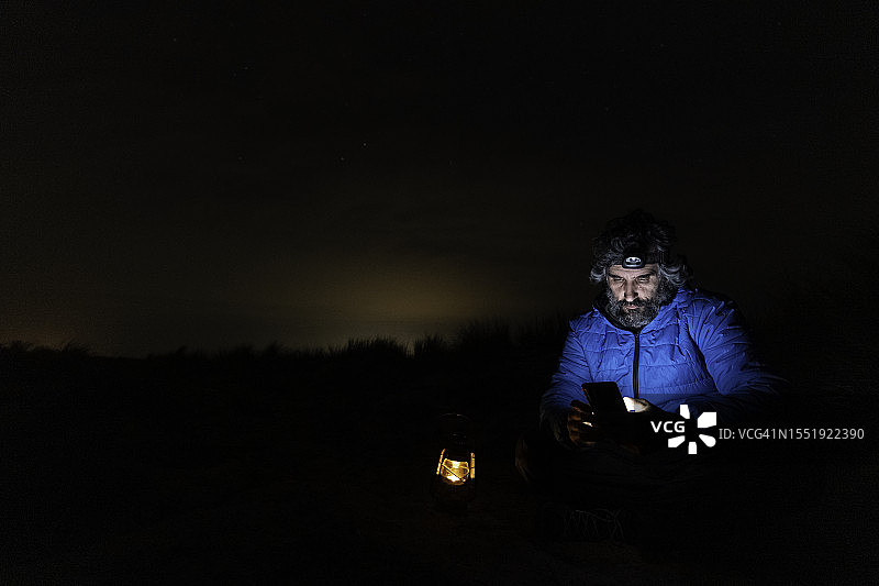 在海边夜晚用手机的男人图片素材