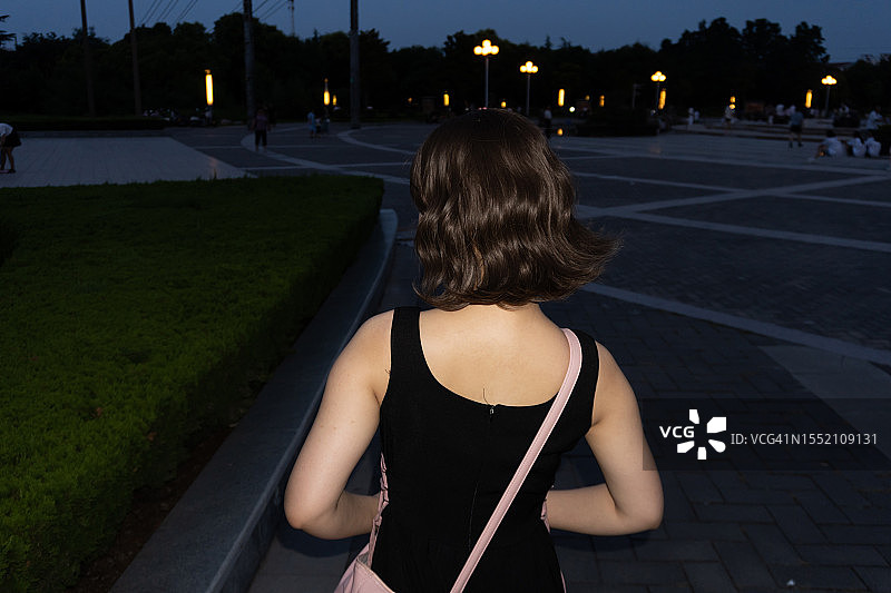 年轻女子背影：鲜明的闪光对比色图片素材