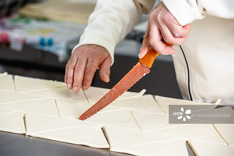 在厨房工作台上用刀将面团切成三角形图片素材