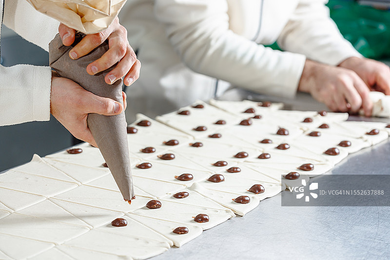 将巧克力奶油挤在面团上并卷起来图片素材