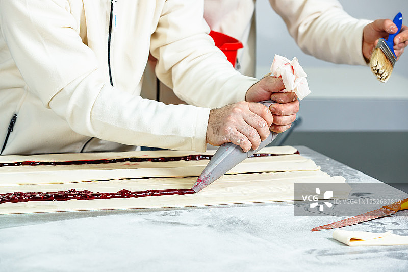 将水果糖浆挤在面团上并用刷子涂抹图片素材