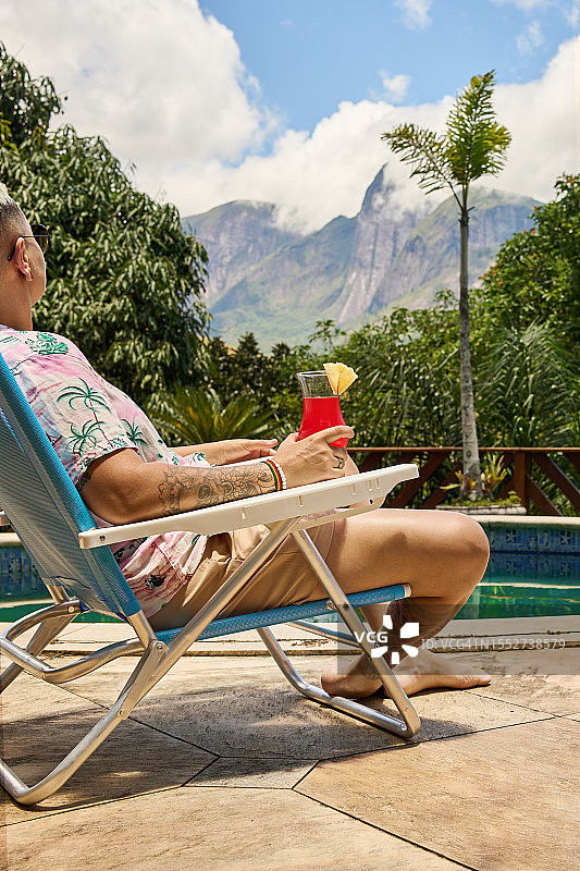 在度假村泳池边喝鸡尾酒的女子图片素材