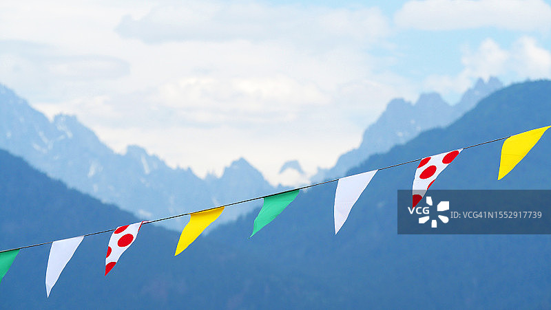 环法自行车赛四色队服旗帜，背景是法国上萨瓦省的模糊山景图片素材