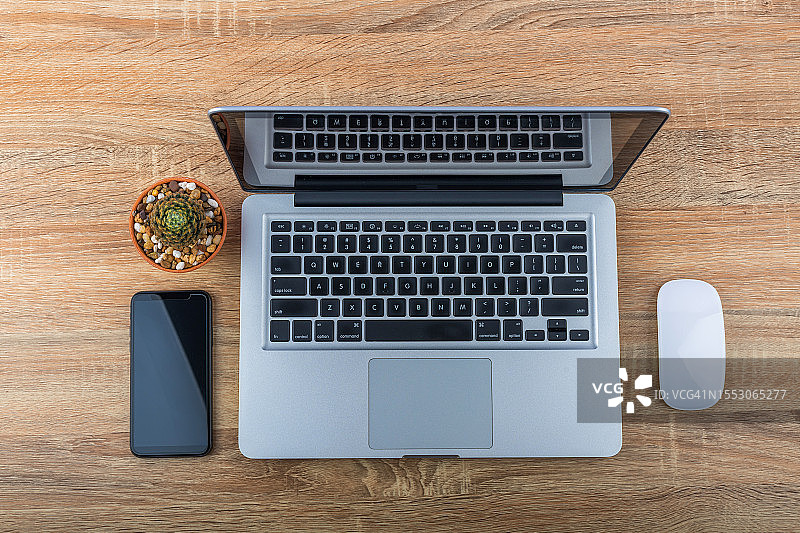木桌上的电脑笔记本电脑模型，屏幕空白，智能手机在桌面上工作，木纹背景图片素材