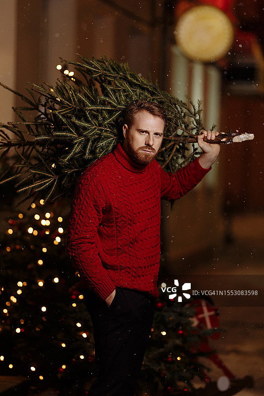 手捧圣诞树行走的时尚男人图片素材