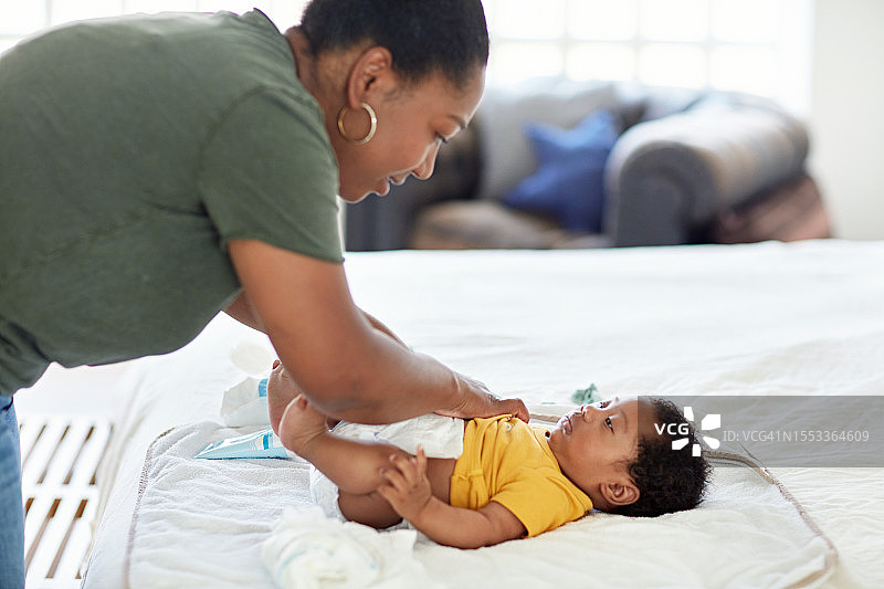 母亲在家更换尿布图片素材