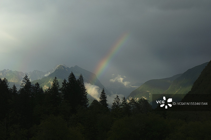 树木和山脉上空中的彩虹图片素材