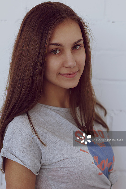 站在墙边微笑的年轻女子肖像图片素材