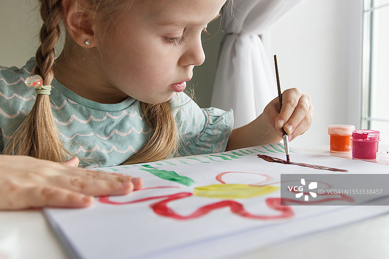 在乌克兰，女孩在桌旁纸上绘画的特写图片素材