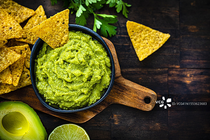 墨西哥美食：鳄梨酱和玉米片，深色木桌俯视图图片素材