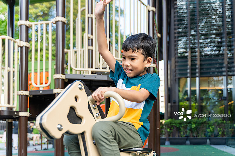 在操场上玩玩具马的小男孩图片素材