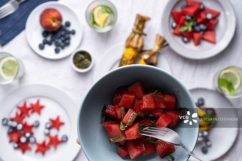 享用西瓜沙拉特写：搭配新鲜水果和浆果的夏季野餐食品，纯素餐背景图片素材