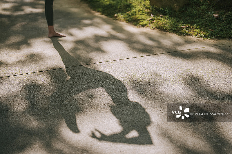 在公园周末早晨练习瑜伽的亚洲女人影子图片素材