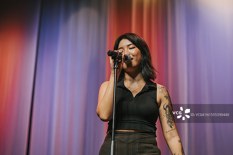 年轻的中国籍亚洲女性独唱歌手在舞台上表演图片素材
