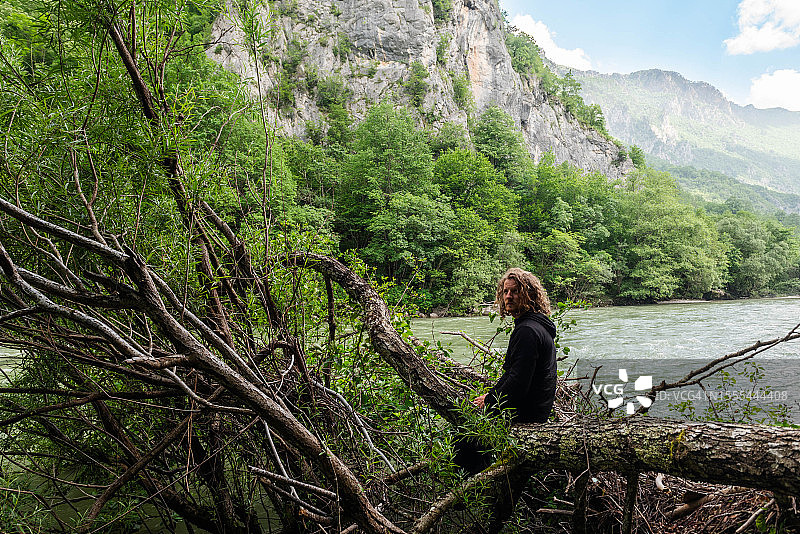 男人坐在杜米托尔国家公园塔拉河边倒下的树上图片素材