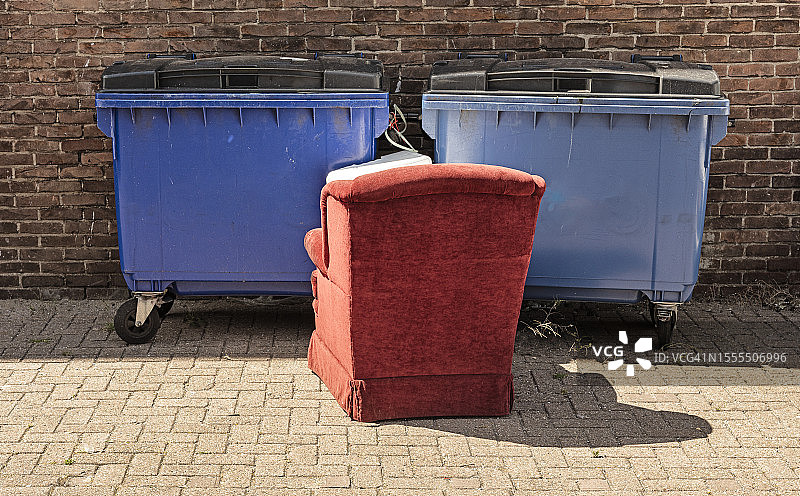 红色软垫椅子位于两个塑料垃圾箱前图片素材
