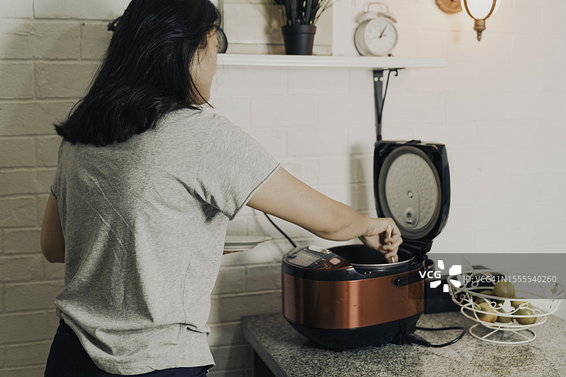 亚洲女人在电饭煲里准备米饭图片素材