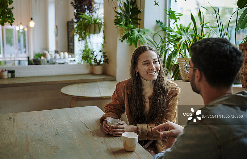 微笑的年轻女人在约会时与男人喝咖啡图片素材
