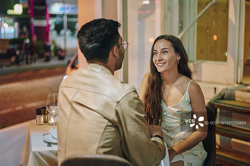 在晚餐约会期间与年轻男子聊天的年轻微笑女人图片素材
