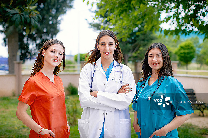 在养老院花园中摆姿势的三位微笑的护士图片素材