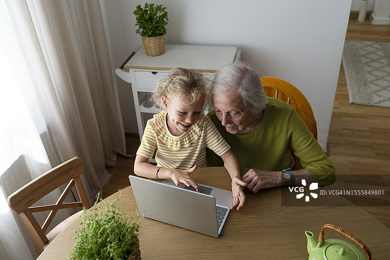 在家中，孙女向祖母展示笔记本电脑图片素材