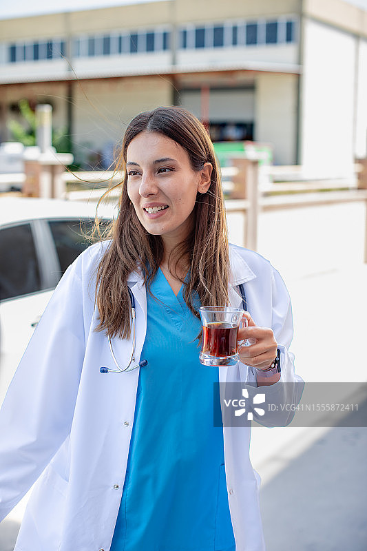 清爽休息：年轻女医生在医院花园里享受茶和交谈图片素材