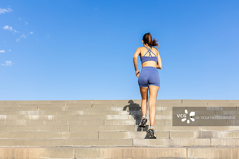 年轻女子在夏季户外慢跑上楼梯的背影图片素材