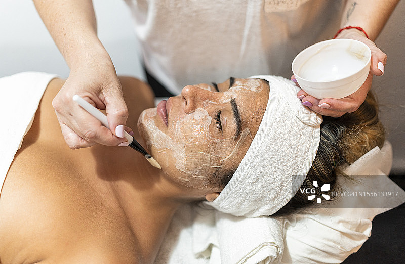女人使用面部和颈部抗衰老泥膜图片素材