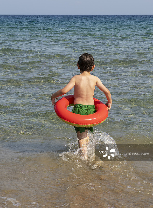 带着游泳圈跑向大海的小男孩图片素材