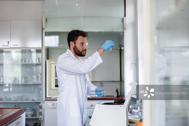 拉丁裔男科学家在实验室里拿着试管观察图片素材