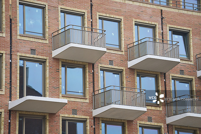 带砖墙的住宅楼外观，封闭的窗户和阳台，低角度视图图片素材