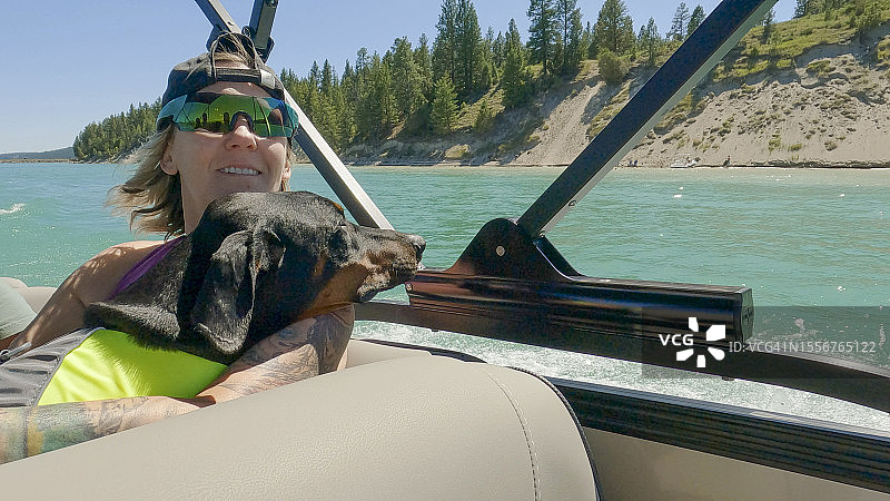 女人和狗在摩托艇上探索湖泊图片素材