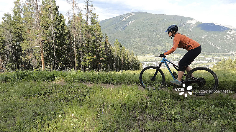 女子在森林和山脉上方骑电动山地自行车图片素材