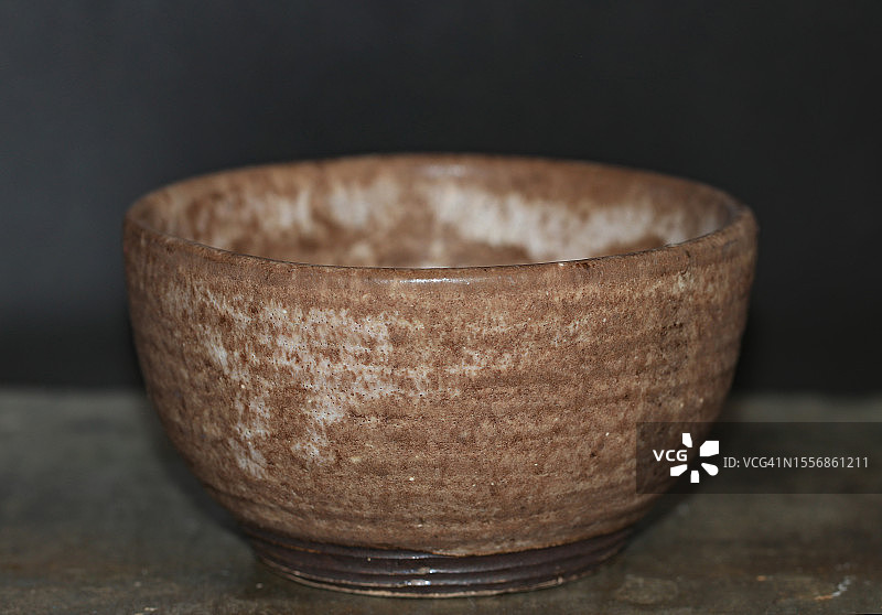 黑色背景下的棕色旧陶碗图片素材