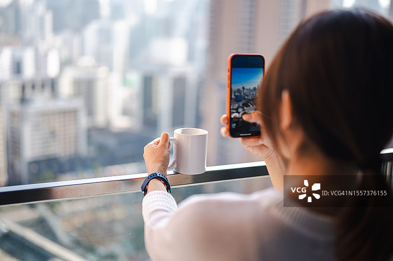 亚洲女性博主在阳台享受咖啡的宁静时刻图片素材