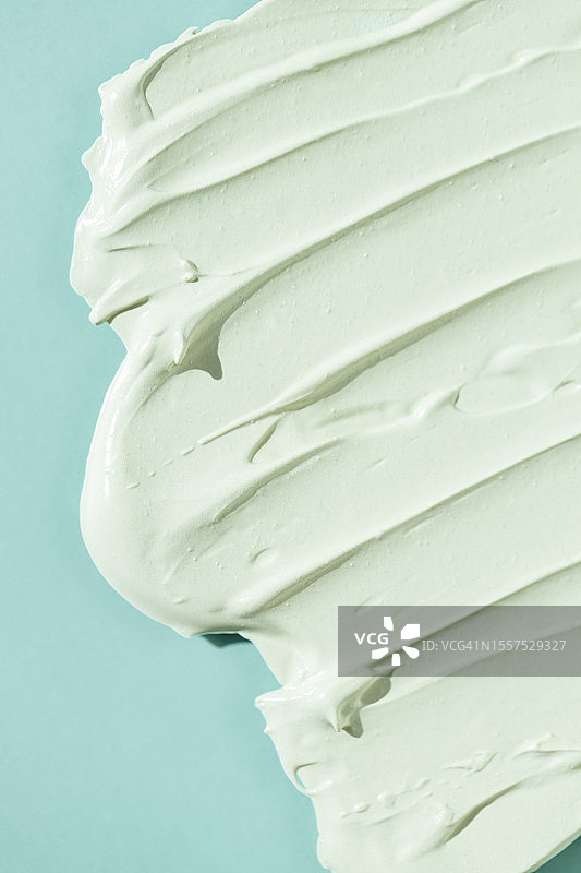 蓝绿色背景上的化妆品霜或磨砂膏图片素材