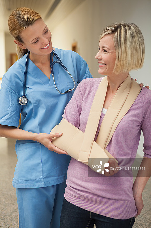 护士面带微笑，搀扶着手臂骨折的病人图片素材