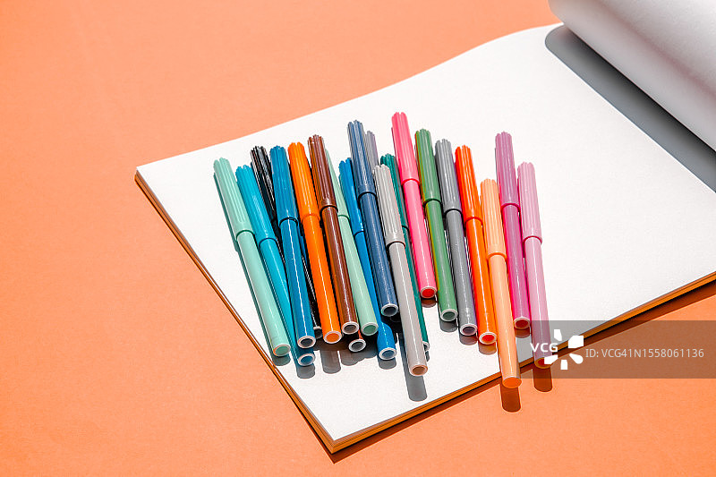 橙色背景上的彩色马克笔和相册纸图片素材