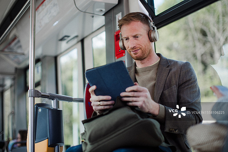 乘坐公共汽车旅行的英俊红发男子，站立并握着扶手图片素材