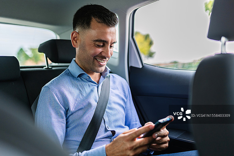 年轻男乘客在出租车上使用手机图片素材