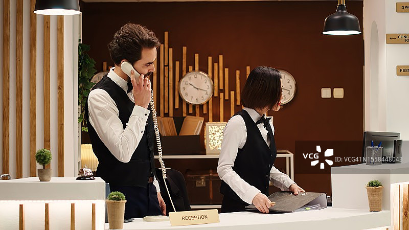 两名酒店工作人员在酒店接待区工作的特写图片素材